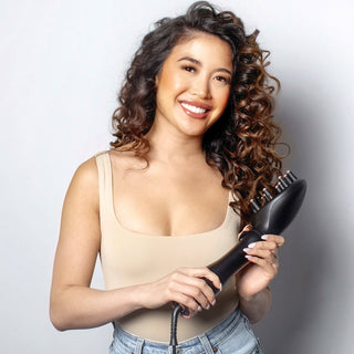 Image of brunette model with curly Ringletts holding the blow brush midnight rose with the diffuser attachment on.