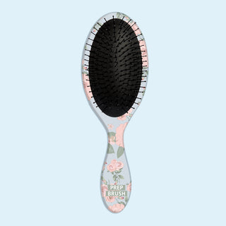 Image of blue hair brush with pink flowers and greenery on blue background