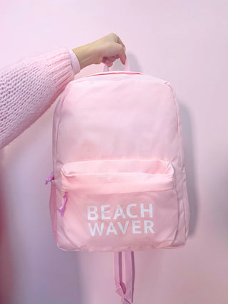 Image of light pink backpack that says Beachwaver in white on the front pouch