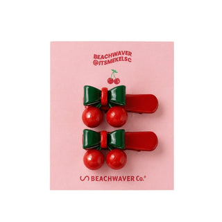 Two red and green hair clips with cherry design on a white background.
