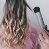 Video of model with blonde hair having her hair curled by the Beachwaver S1.25 and then brushed out with a beachwaver brush 