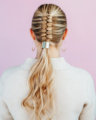 Image of blonde model with braided hairstyle that leads into a long ponytail with a silver hair piece.