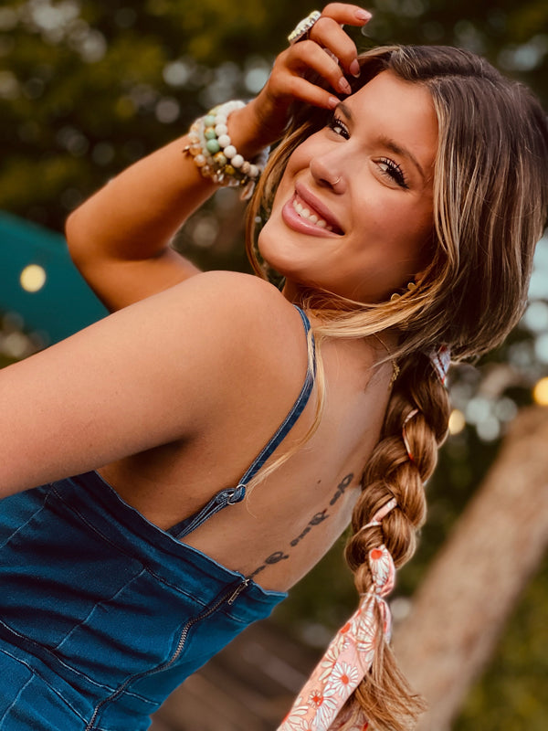 Image of happy brunette model with a long braid that has the pink daisies silk scarf braided into it