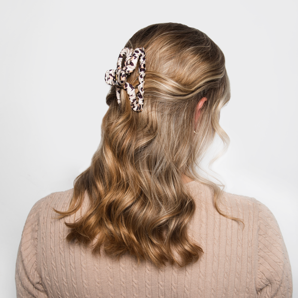 Image of model with golden hair styled by Beachwaver hair tool pulled away from her face using the catwalk fabric claw clip in cat print.