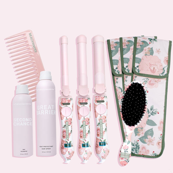 Image of floral pro collection which includes a pink wide tooth comb, a pink aerosol bottle of second chance dry shampoo, another pink aerosol bottle of great barrier heat protectant hairspray, all three sizes in the Floral Beachwaver S series  of the pink and white with pink flowers and greenery, three storage pouches to hold those Beachwaver's and those come in pink and white with pink flowers and greenery, and lastly a white brush with pink flowers and greenery 