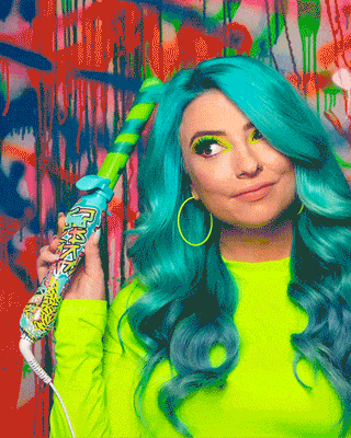 GIF of model with teal hair and neon long sleeve shirt curling her hair using the graffiti b1 rotating curling iron.