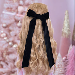 image of long golden hair styled in with a Beachwaver hair-tool pulled away from the face in a black velvet bow.
