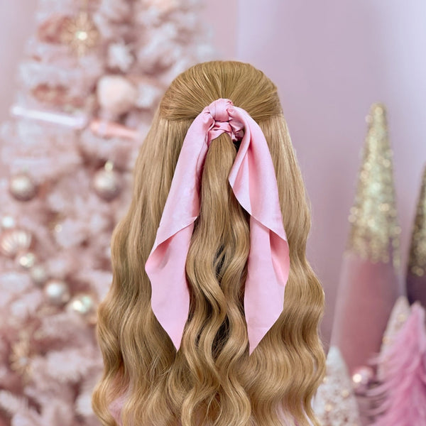 image of long golden hair styled in with a Beachwaver hair-tool pulled away from the face in a pink Silky hairscarf.