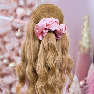 image of long golden hair styled in with a Beachwaver hair-tool pulled away from the face in a pink Silky Scrunchie.