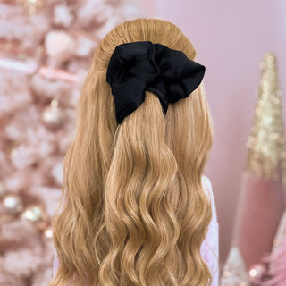 image of long golden hair styled in with a Beachwaver hair-tool pulled away from the face in a black Silky Scrunchie.
