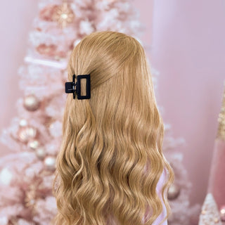 image of long golden hair styled in with a Beachwaver hair-tool  pulled away from the face in a black square Clawclip.