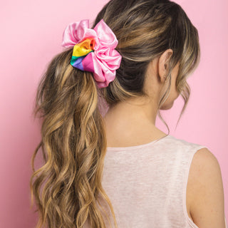 Image of brunette model with her long hair styled by Beachwaver hair tool and pulled away from her face in the pink and rainbow silk jumbo scrunchie
