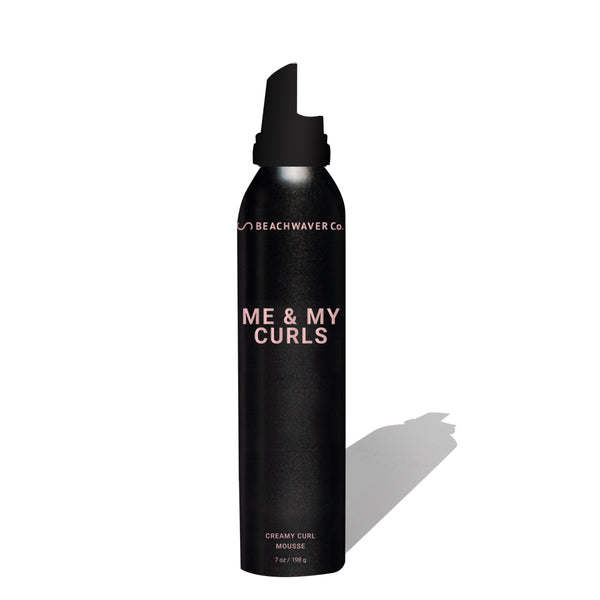 Me & My Curls creamy curl mousse 7 oz image on a white background. Product has a black dispenser and black can with text in a pinky rosegold.
