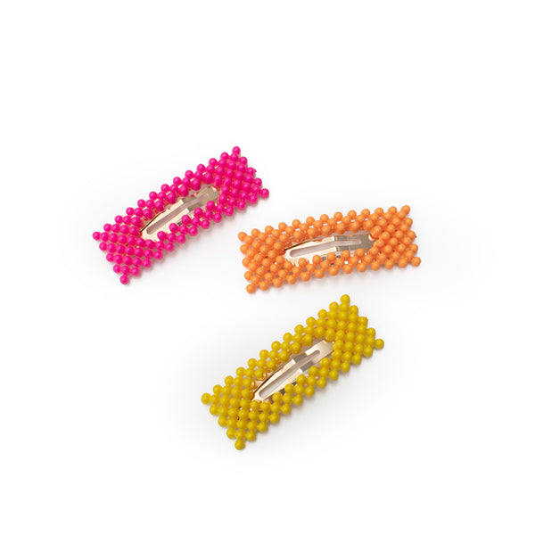 Image of three bumpy hair clips in the colors neon pink, neon orange, and neon yellow.