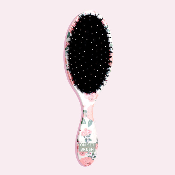 Image of White hair brush with pink flowers and greenery on a pink background