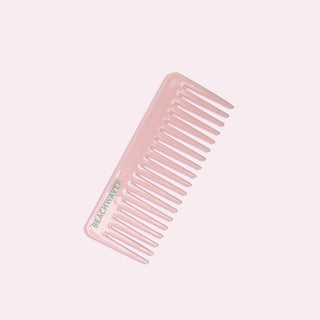 Image of pink wide tooth comb with a Green Beachwaver logo on it on pale pink background