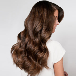 Image of model with brown hair showing off her long beachy waves that were styled with the Beachwaver® pro 1 and Beachwaver® shine squad.