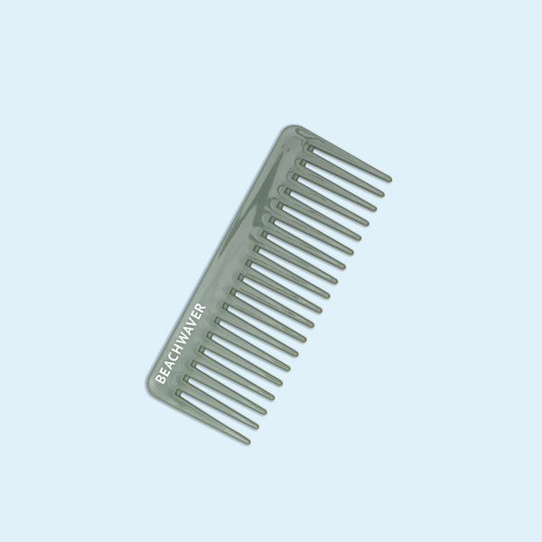 Image of green wide tooth comb with white Beachwaver logo on it on pale blue background