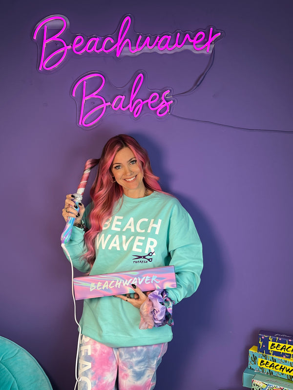 Image of Ceo Sarah Potempa Wearing a Teal Beachwaver Hoodie and holding the Prism Beachwaver B1.