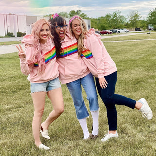 Beachwaver founders wearing love hoodie (a pink hoodie with a rainbow down the center)